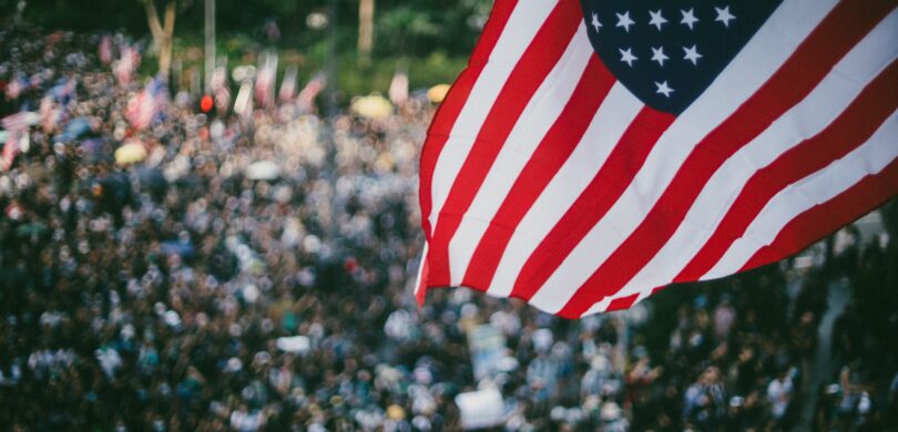 A crowd of people with the American flag in the foreground.